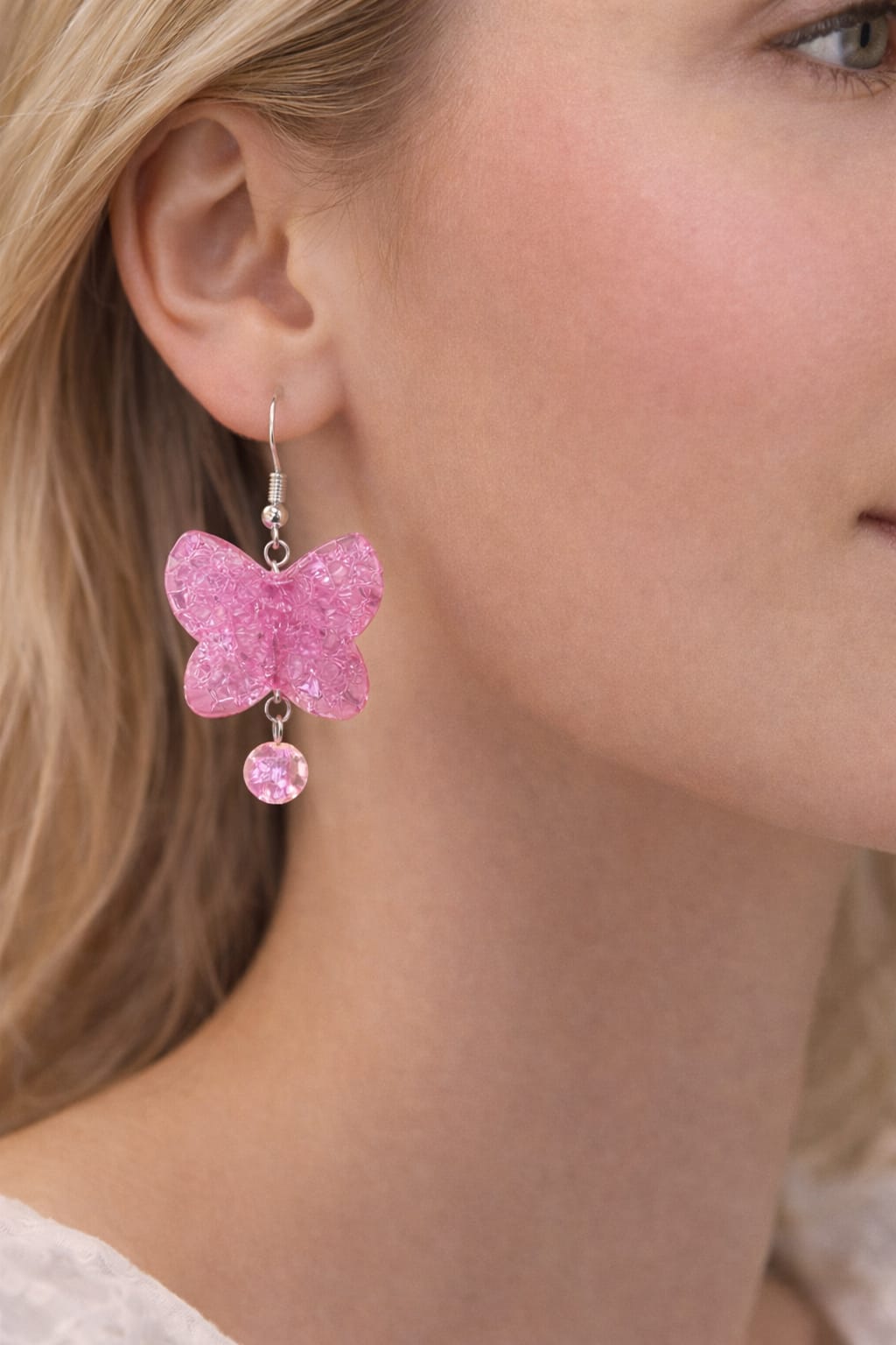Close-up of pink acrylic butterfly charm earrings with shimmering glass beads