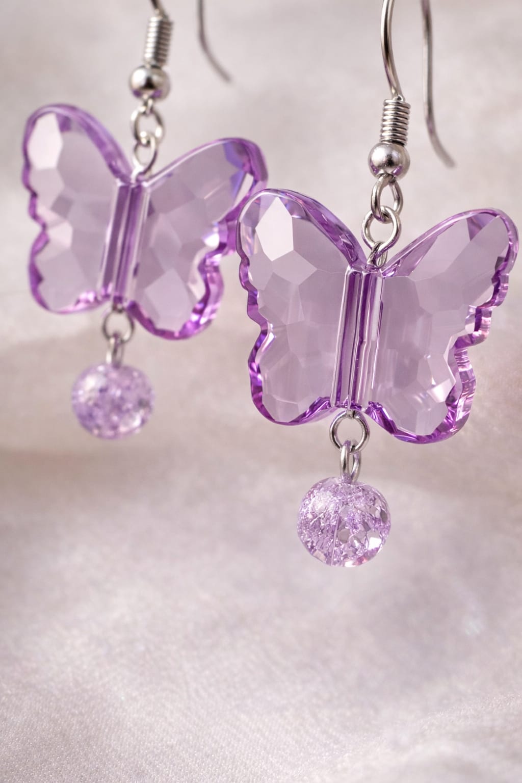 Soft lavender butterfly earrings catching light with shimmering bead accents
