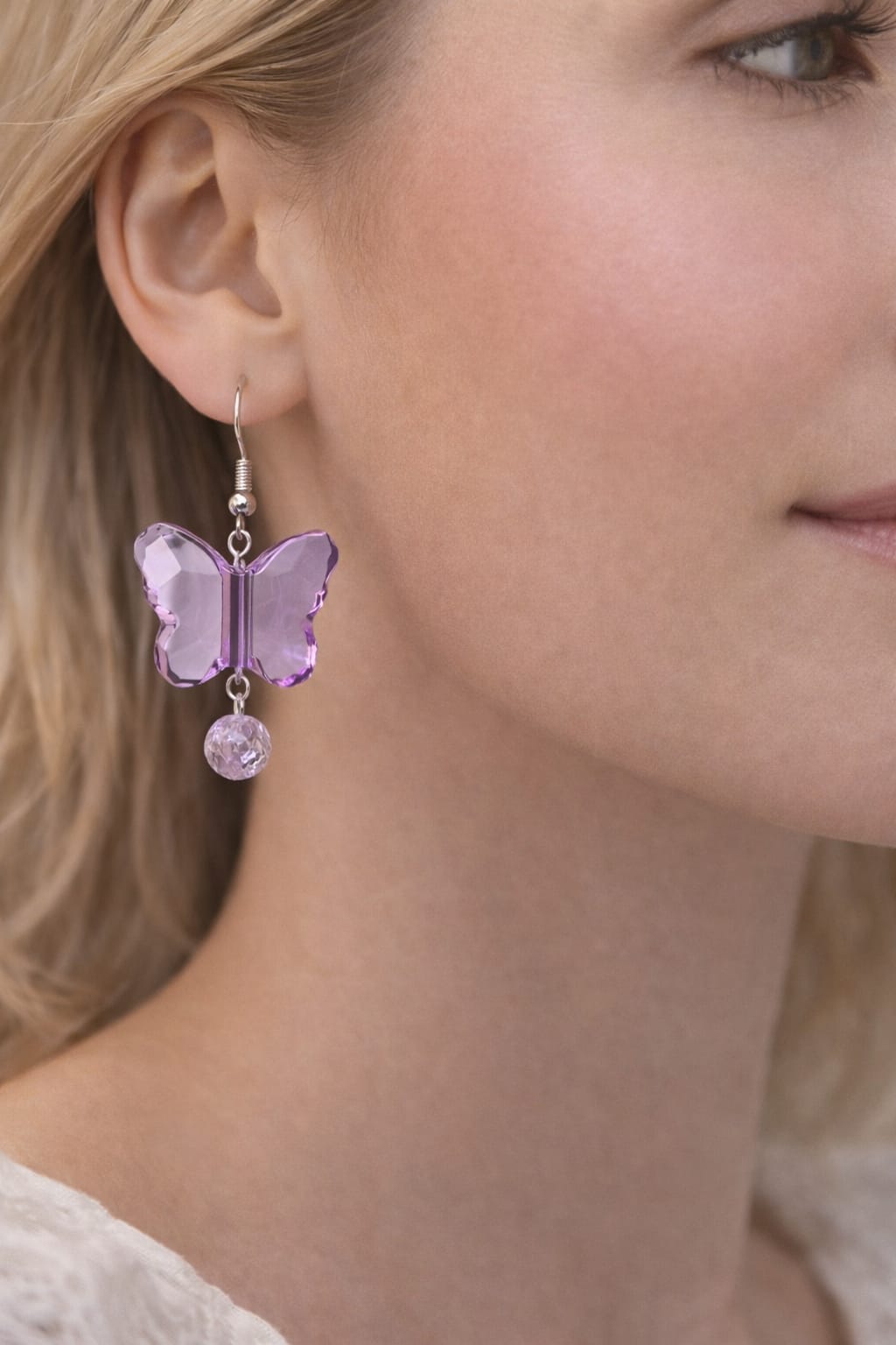 Close-up of lavender butterfly charm earrings with shimmering bead detail