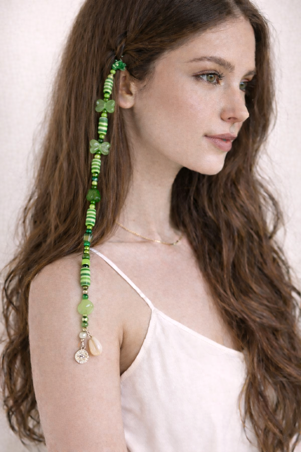 Close-up of green beaded hair clip with pearl details and dangling charms