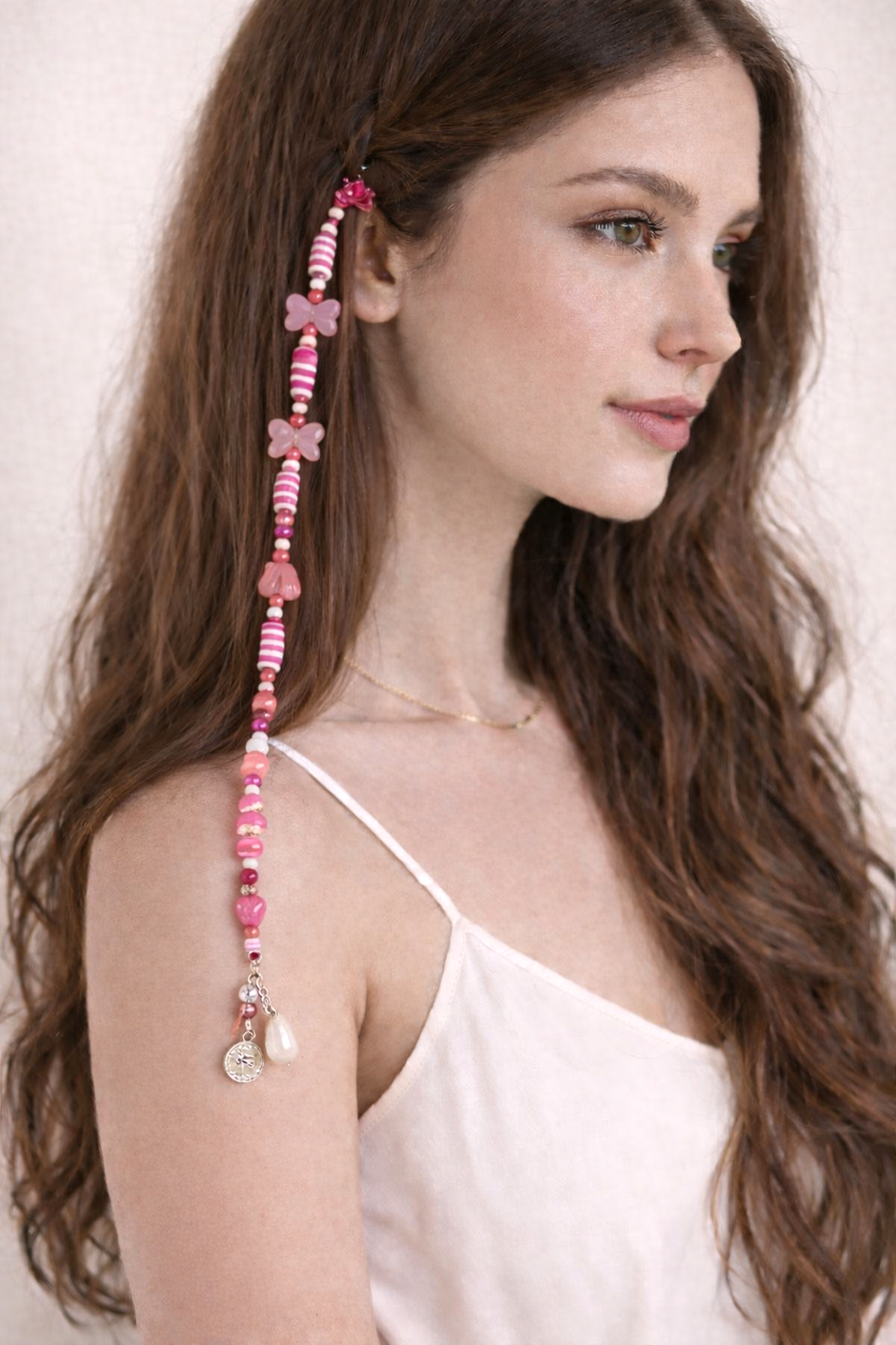 Close-up of soft pink beaded hair clip with glossy bow detail and dangling charms