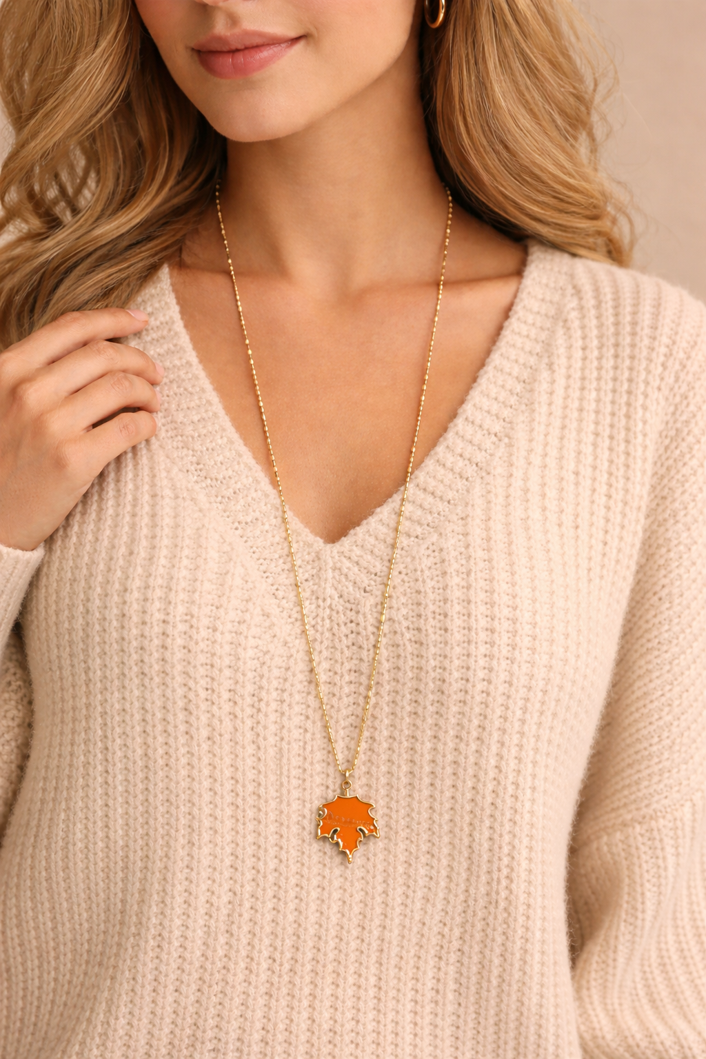 Close-up of orange maple leaf pendant on gold glass bead chain